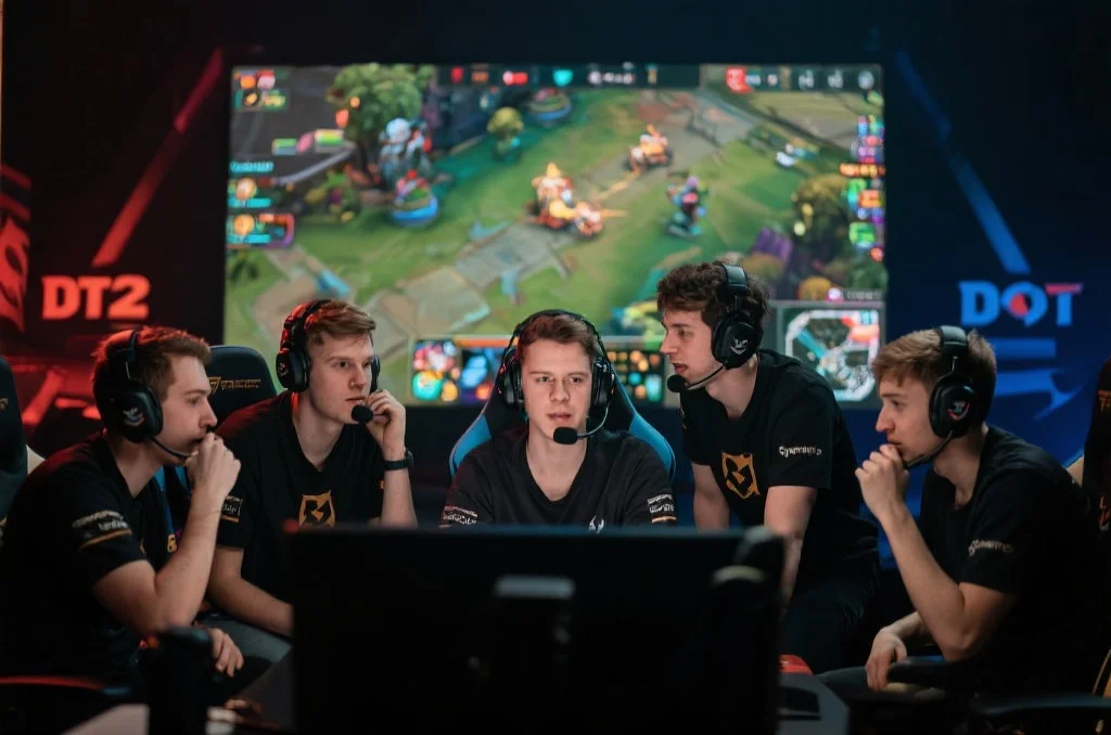 五名DOTA2玩家在团队语音沟通中，为一场激烈团战做战术部署，每个人都专注且充满斗志